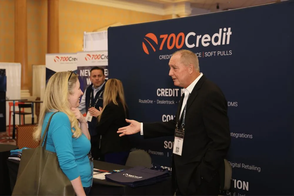 An attendee greeting a visitor at a credit-services booth
