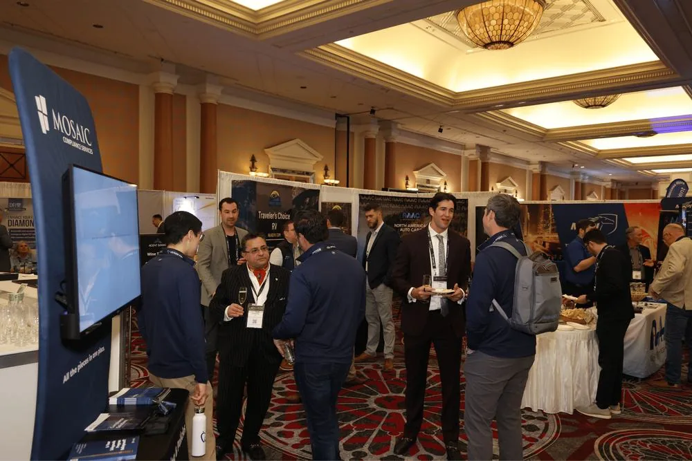 Attendees with drinks around the booths at the evening reception